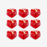 Red heart-shaped candies with white swirl patterns on a white background